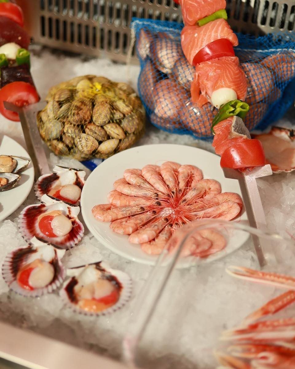 Marisco fresco de la vitrina: gambas, vieiras y mejillones sobre hielo