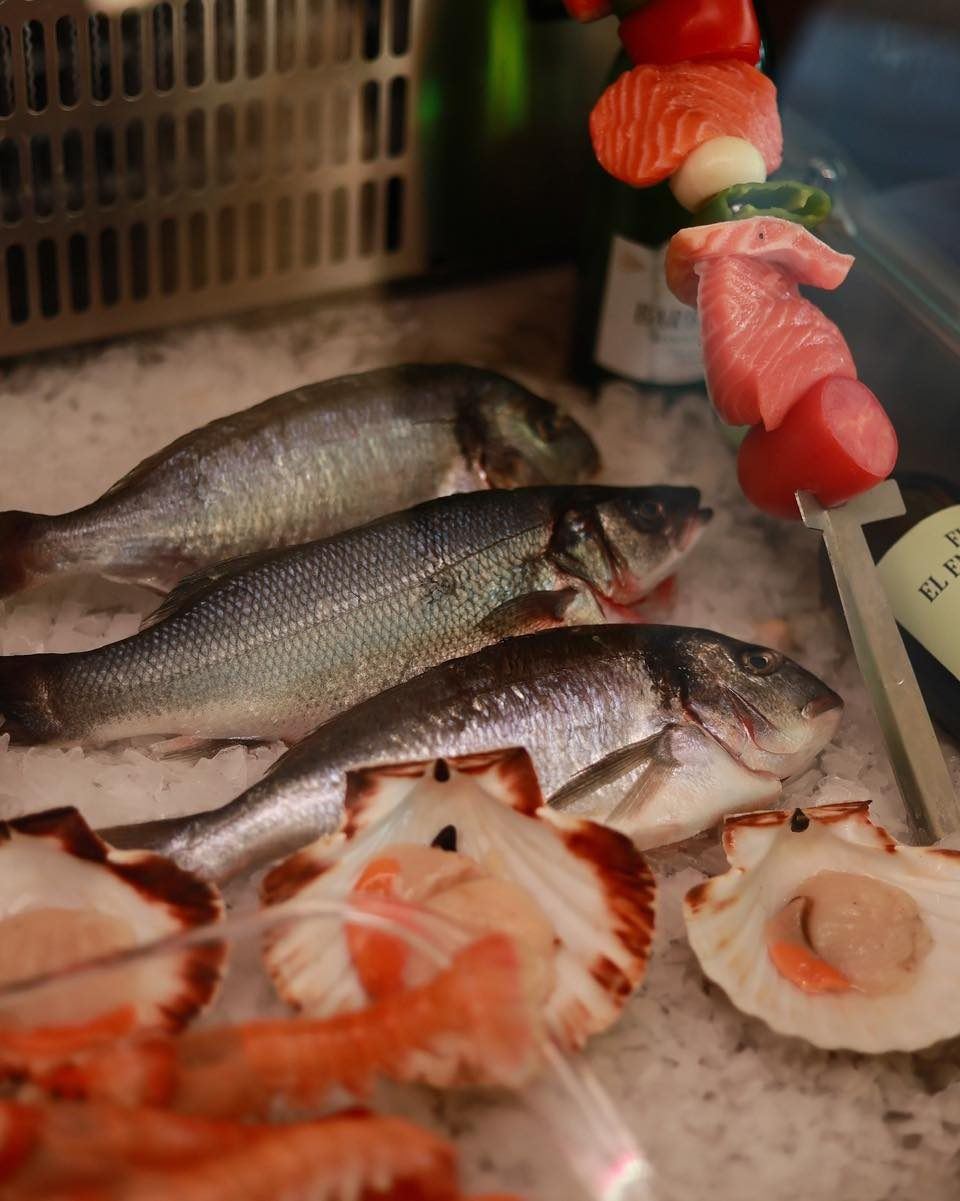 Pescado fresco de lonja sobre hielo, junto a vieiras y gambas