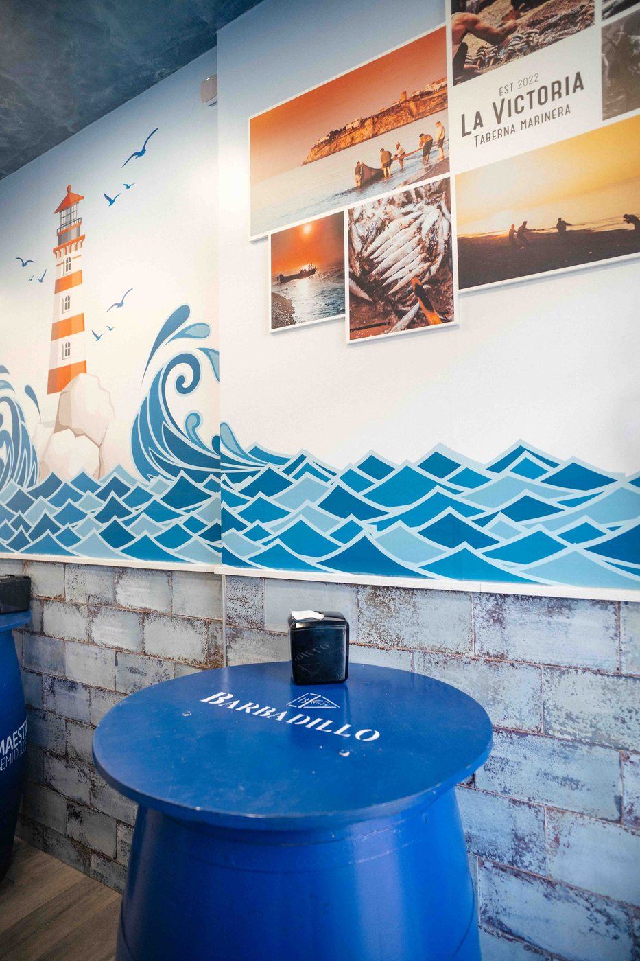 Rincón decorado con fotografías marineras y mural del faro en La Victoria